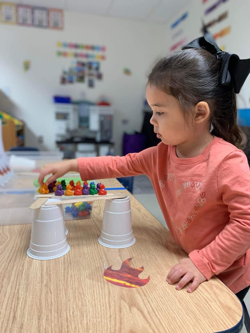 A girl building a bridge for counting bears at the classroom table
