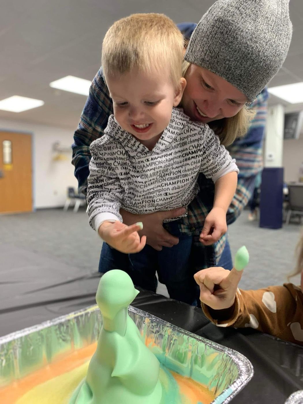 A parent and child laughing together over a foam science experiment at a family event