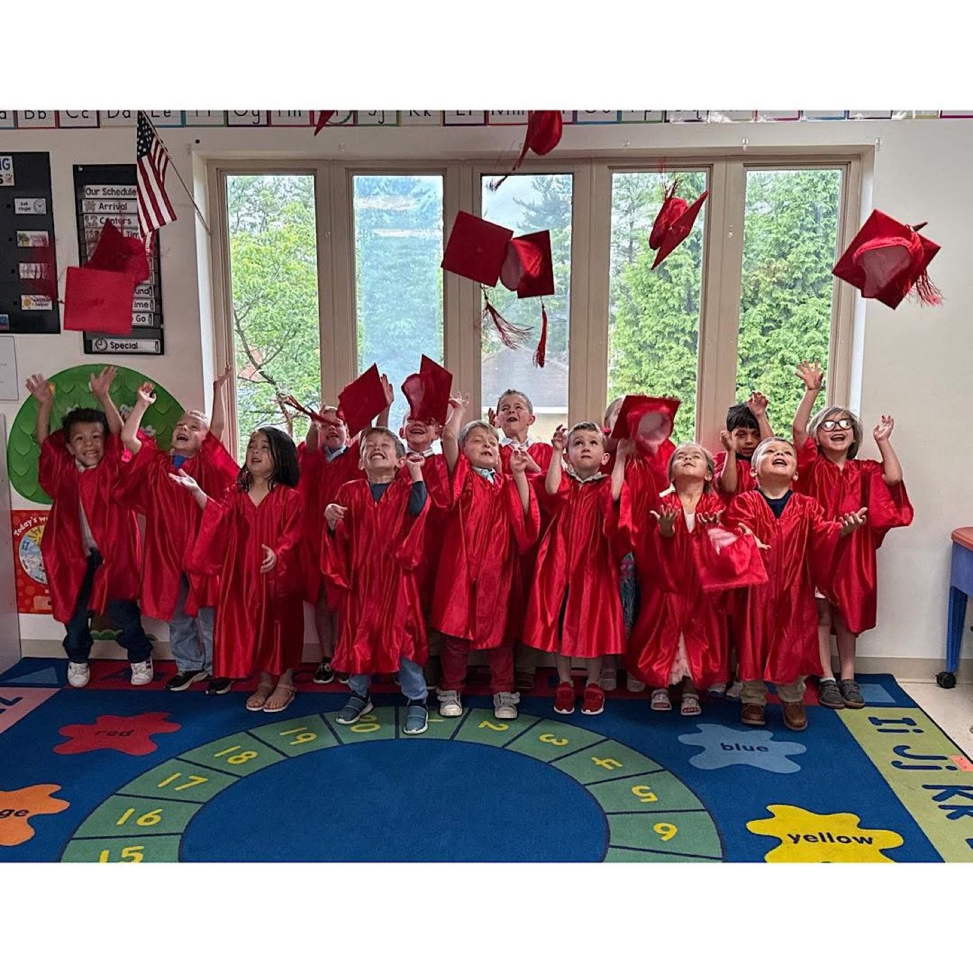 Graduates in red caps and gowns tossing their caps in the air