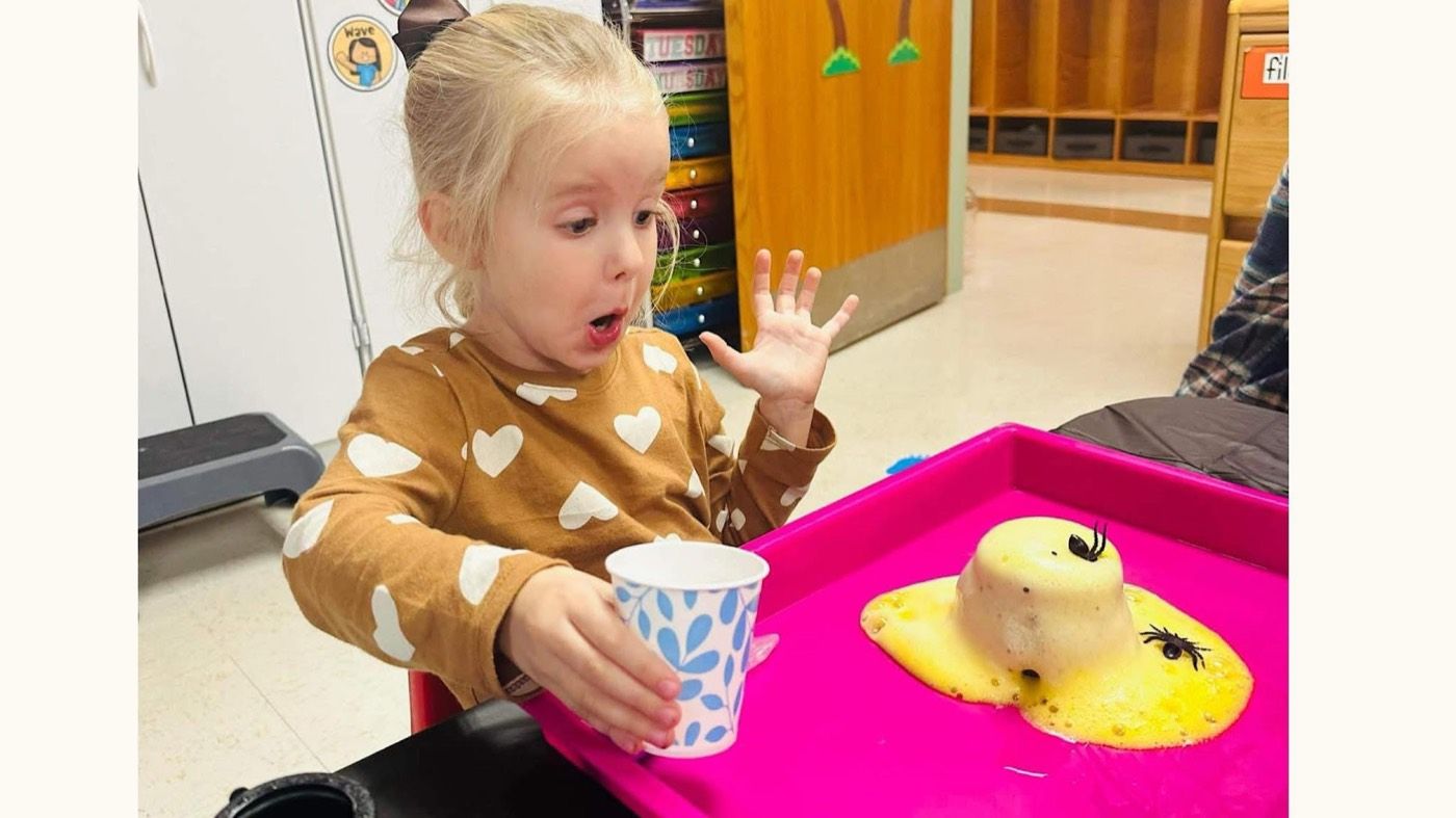 A girl amazed by a fizzing volcano science experiment